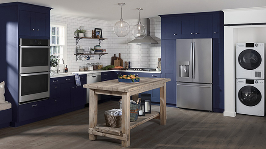 A conservative but stylish kitchen. GE Appliances with a stainless steel finish are installed in simple blue cabinetry.