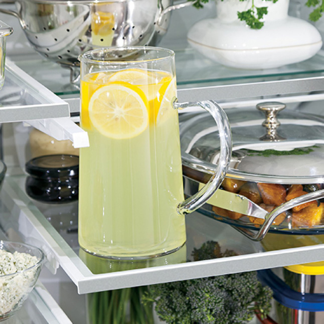 An interior shot of the fridge shows that the top shelf slid into itself, providing extra space to store a tall pitcher on the lower shelf