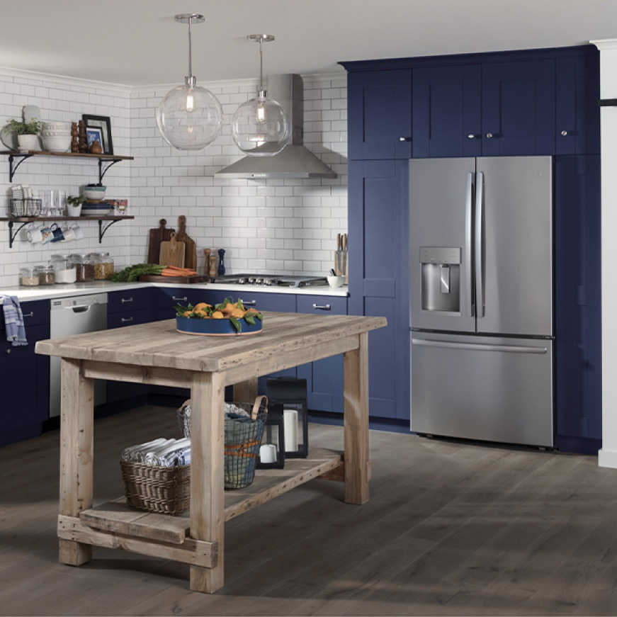 A conservative but stylish kitchen. GE Appliances with a stainless steel finish are installed in simple blue cabinetry.