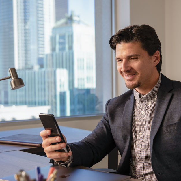 Man sitting in office looking at smartphone. Man sitting in office looking at smartphone.