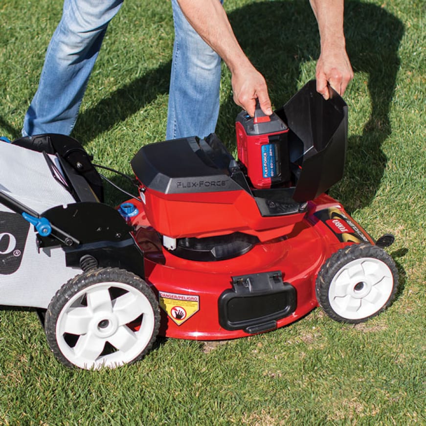 person easily putitng a battery into the mower person easily putitng a battery into the mower