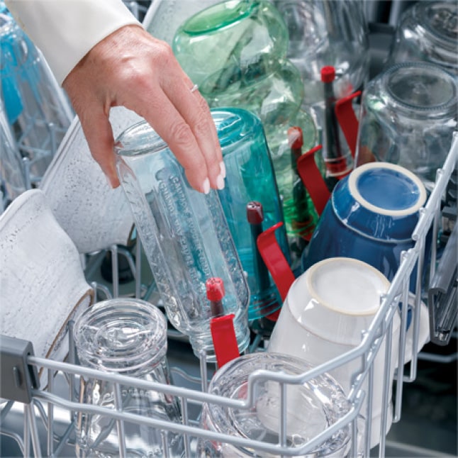 Shot of woman's hand placing a bottle on the bottle jet inside the dishwasher