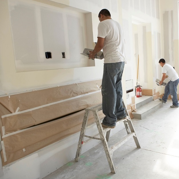 Two men putting joint compound on wallboard Two men putting joint compound on wallboard