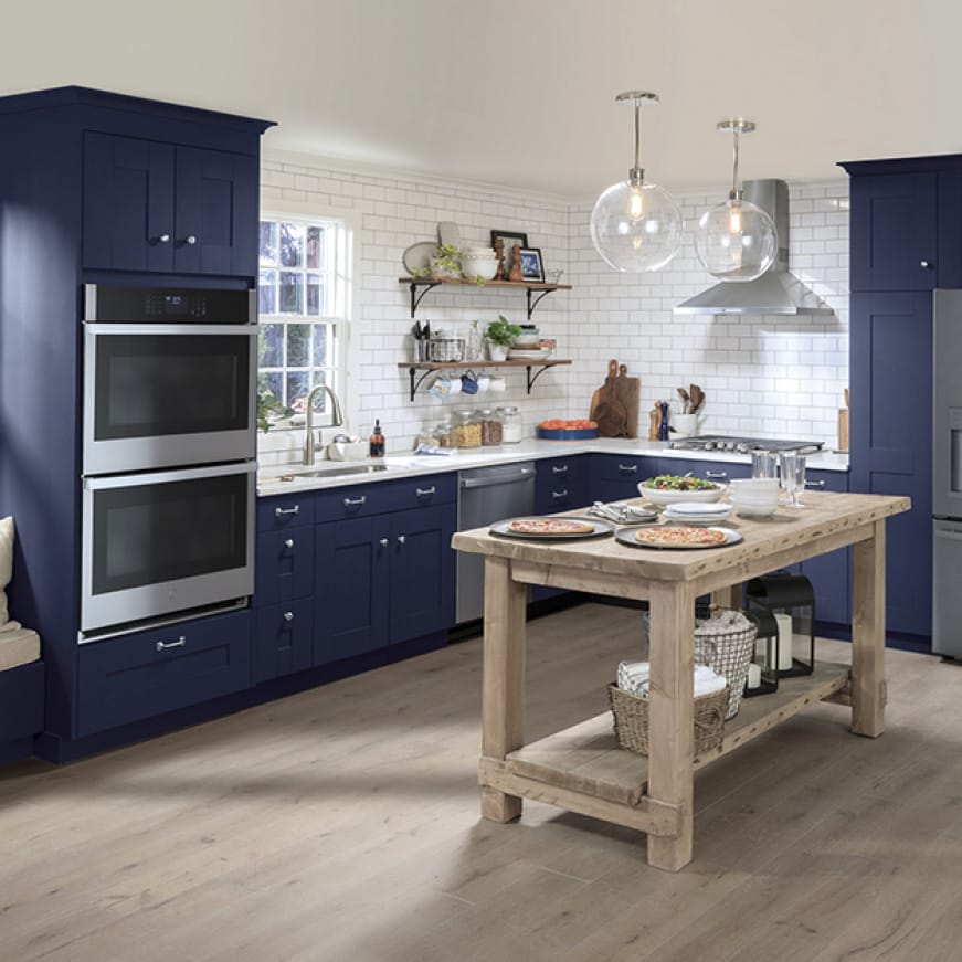 A conservative but stylish kitchen.GE Appliances with a stainless steel finish are installed in simple blue cabinetry.